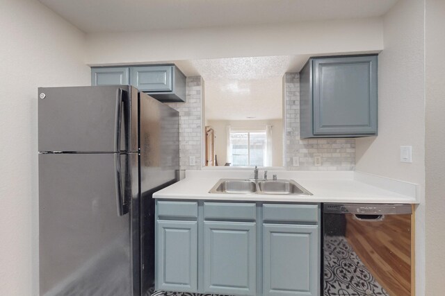 kitchen featuring backsplash, sink, black dishwasher, and fridge