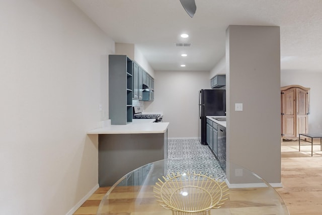 kitchen featuring dishwasher, black fridge, kitchen peninsula, light hardwood / wood-style flooring, and white range with gas stovetop