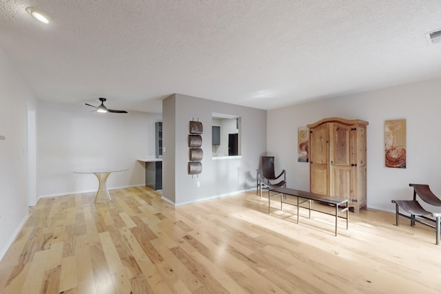 interior space with ceiling fan, a textured ceiling, and light wood-type flooring