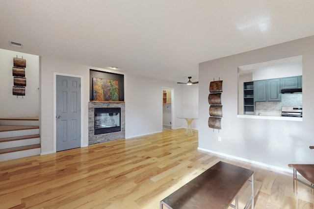 unfurnished living room featuring a fireplace, light wood-type flooring, and ceiling fan