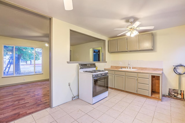 kitchen with sink, decorative backsplash, ceiling fan, light tile patterned flooring, and white range with gas stovetop