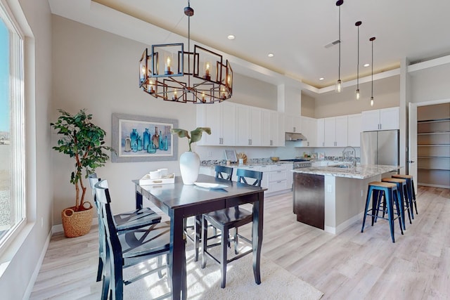 kitchen with appliances with stainless steel finishes, white cabinets, a kitchen island, and decorative light fixtures