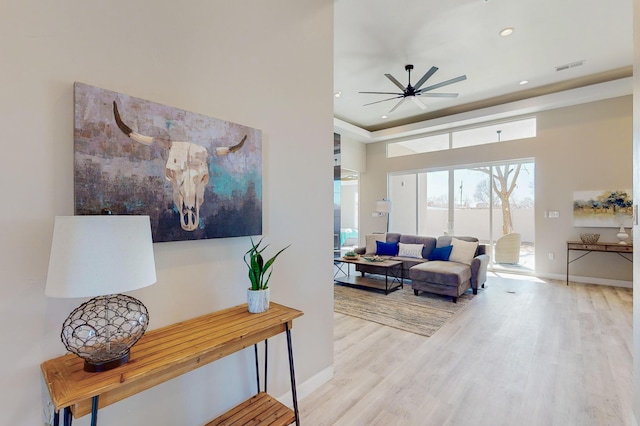 living room with a high ceiling, ceiling fan, and light hardwood / wood-style flooring