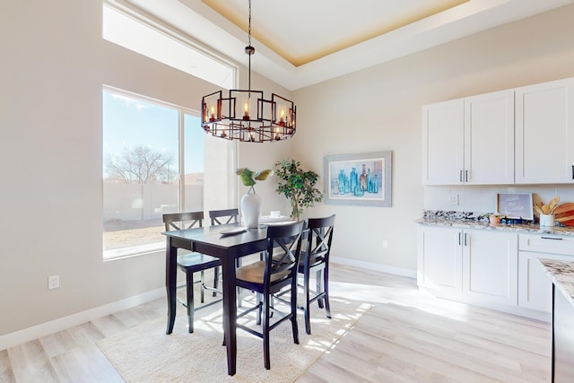 dining room with an inviting chandelier, light hardwood / wood-style floors, and a tray ceiling