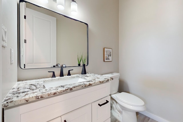 bathroom with toilet, hardwood / wood-style floors, and vanity