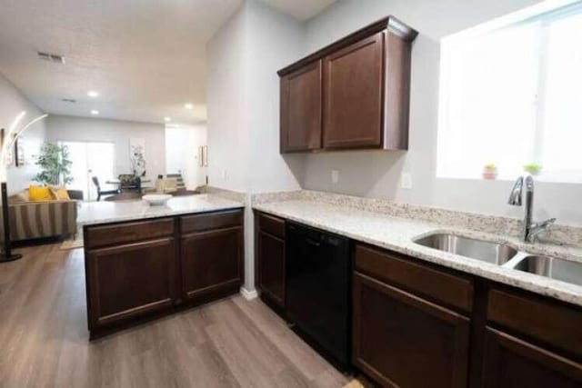 kitchen featuring sink, black dishwasher, kitchen peninsula, light hardwood / wood-style floors, and dark brown cabinets