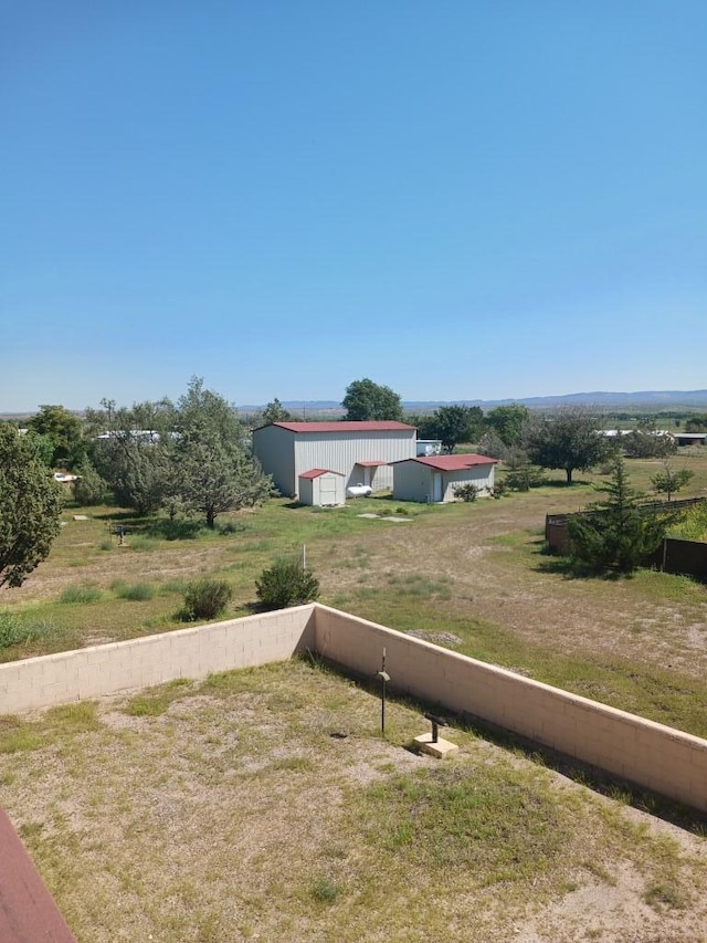 view of yard featuring an outdoor structure and a rural view