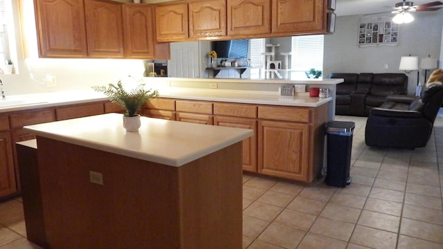 kitchen with sink, light tile patterned floors, kitchen peninsula, a kitchen island, and ceiling fan