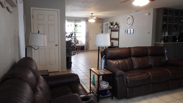 living room featuring ceiling fan, a textured ceiling, and light tile patterned floors