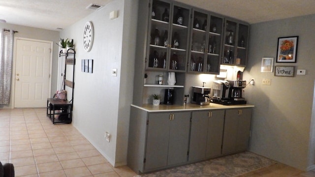 bar with gray cabinets and light tile patterned floors