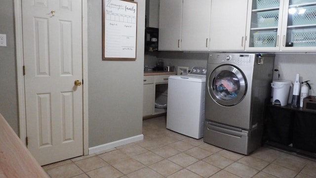 washroom with separate washer and dryer, light tile patterned floors, and cabinets