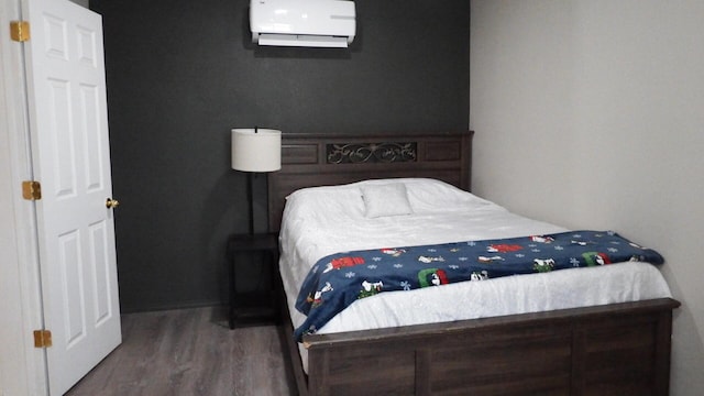 bedroom with hardwood / wood-style floors and a wall unit AC