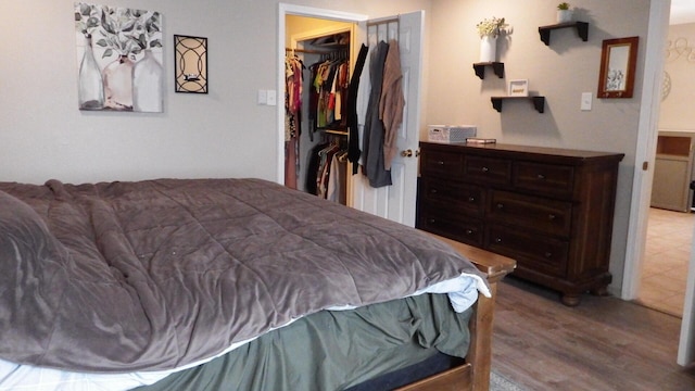 bedroom featuring a walk in closet, light wood-type flooring, and a closet