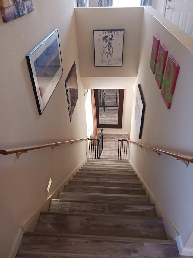 staircase with hardwood / wood-style floors and a high ceiling