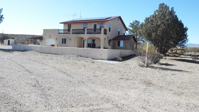 back of property with a balcony and solar panels