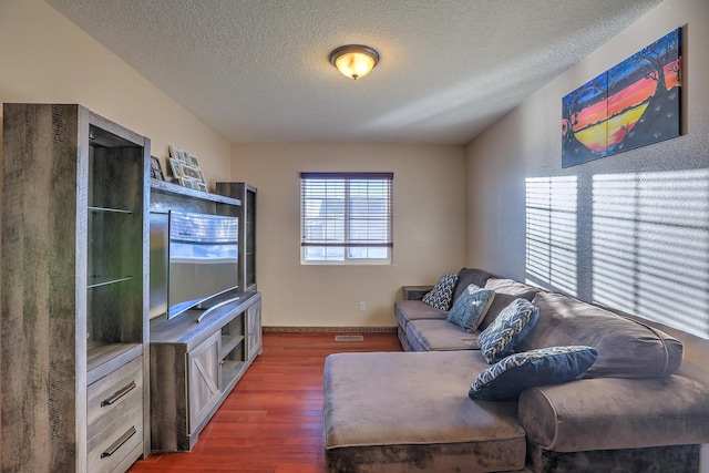 living room featuring dark wood-type flooring and a textured ceiling