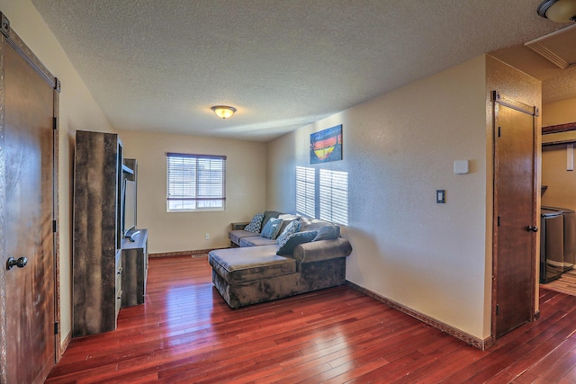 living area with a textured ceiling, a barn door, and dark hardwood / wood-style floors