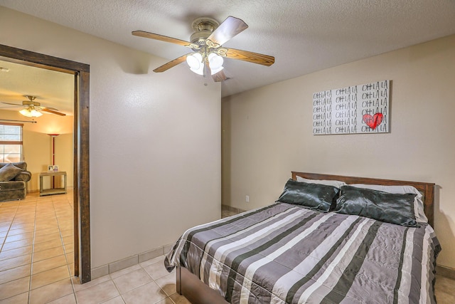 bedroom featuring ceiling fan, light tile patterned floors, and a textured ceiling