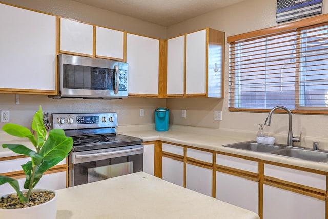 kitchen with white cabinets, appliances with stainless steel finishes, and sink