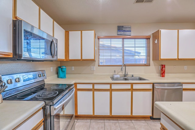 kitchen with sink, white cabinets, light tile patterned flooring, and appliances with stainless steel finishes