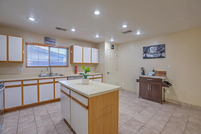 kitchen featuring white cabinetry, sink, a kitchen island, and light tile patterned flooring