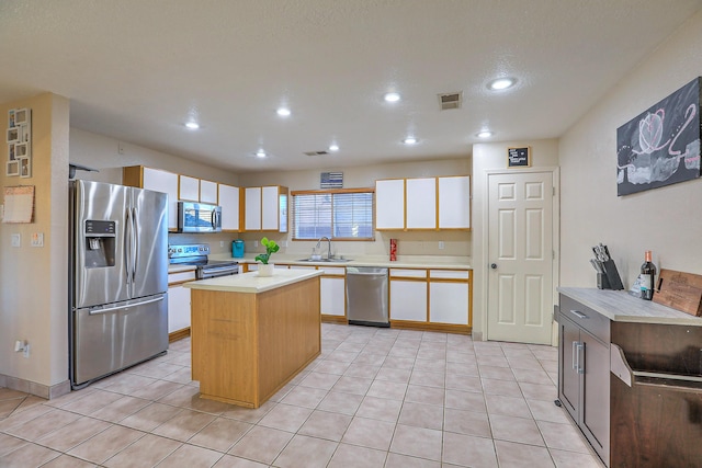 kitchen with a kitchen island, sink, stainless steel appliances, and light tile patterned flooring