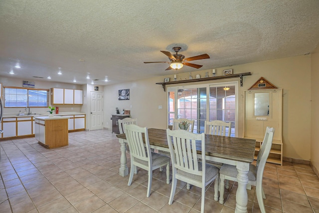 dining area featuring ceiling fan, sink, light tile patterned flooring, and a textured ceiling