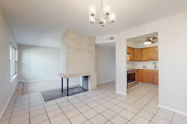 kitchen featuring electric range, a brick fireplace, pendant lighting, a textured ceiling, and light tile patterned floors