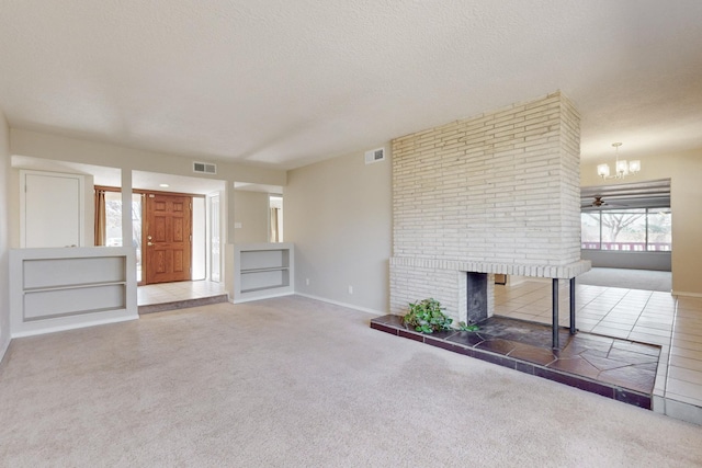 unfurnished living room featuring carpet, a notable chandelier, a textured ceiling, and a brick fireplace