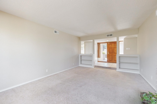 unfurnished living room featuring light colored carpet and a textured ceiling