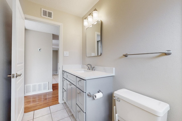 bathroom with toilet, a textured ceiling, vanity, and tile patterned floors