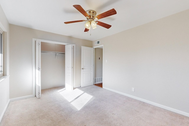 unfurnished bedroom with a closet, light colored carpet, and ceiling fan