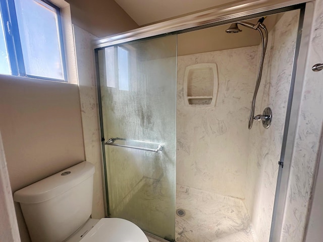 bathroom with toilet and a shower with door