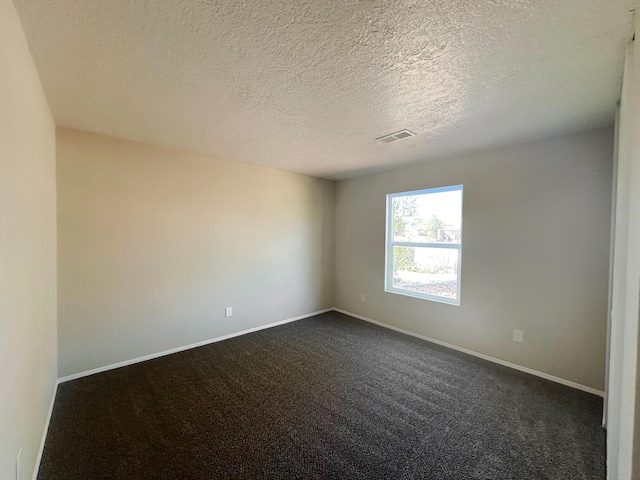 empty room featuring a textured ceiling and dark carpet