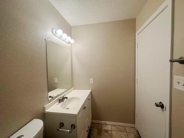 bathroom featuring tile patterned flooring, vanity, toilet, and a textured ceiling