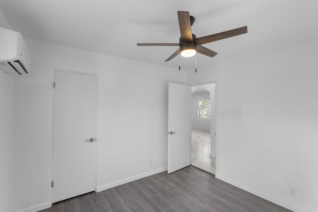 empty room featuring a wall mounted air conditioner, ceiling fan, and dark hardwood / wood-style flooring