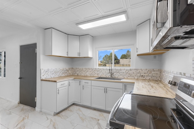 kitchen featuring backsplash, sink, white cabinets, butcher block countertops, and stainless steel electric range