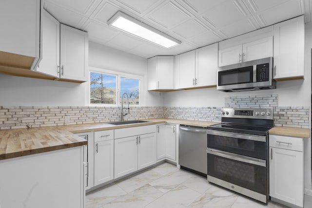 kitchen with backsplash, stainless steel appliances, sink, white cabinetry, and butcher block counters