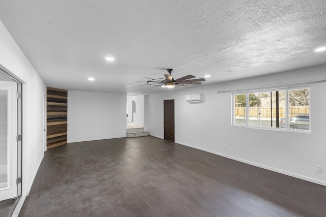 empty room with a textured ceiling, an AC wall unit, and ceiling fan