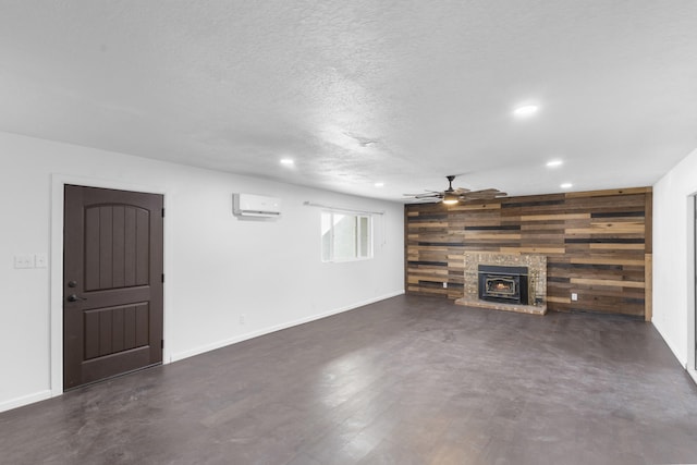 unfurnished living room featuring a wood stove, ceiling fan, a wall unit AC, wood walls, and a textured ceiling