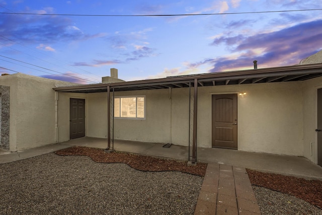 back house at dusk featuring a patio