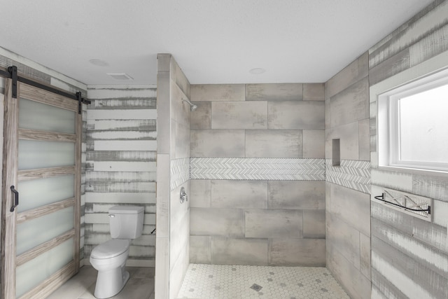 bathroom with toilet and a tile shower