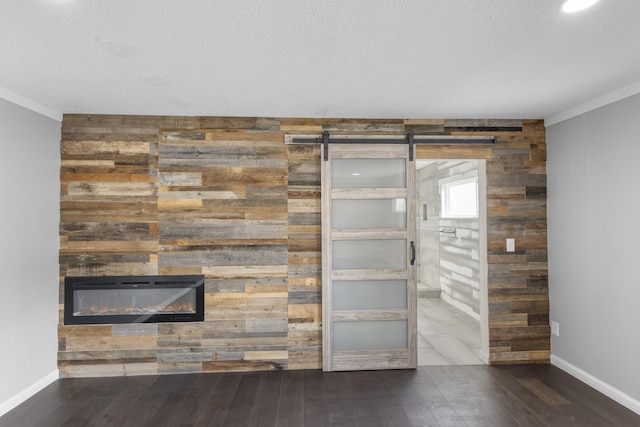 details featuring a barn door, wooden walls, wood-type flooring, and ornamental molding