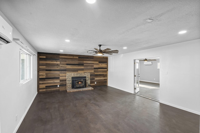 unfurnished living room featuring ceiling fan, a wood stove, a textured ceiling, and wooden walls