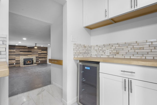 kitchen featuring wood counters, a wood stove, wooden walls, white cabinetry, and beverage cooler