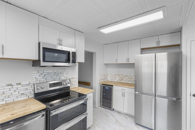 kitchen with wooden counters, appliances with stainless steel finishes, white cabinets, and wine cooler