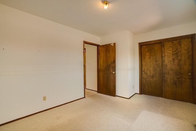 unfurnished bedroom featuring light colored carpet and a closet