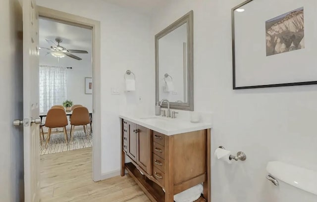 bathroom with ceiling fan, toilet, wood-type flooring, and vanity