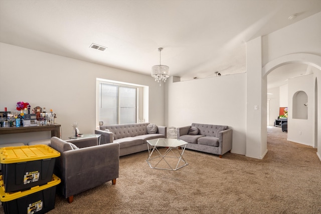 carpeted living area featuring arched walkways, visible vents, and an inviting chandelier