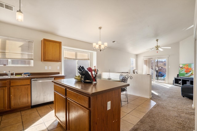 kitchen with light carpet, a sink, open floor plan, stainless steel dishwasher, and dark countertops